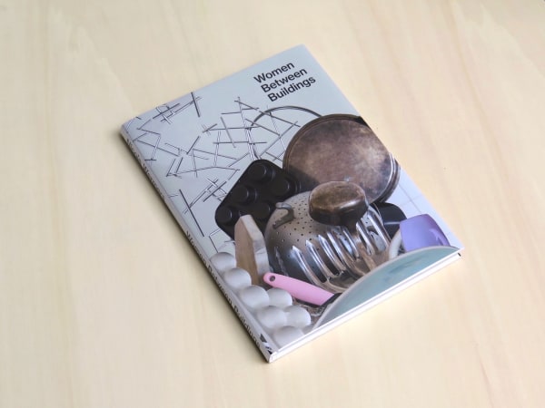 book Women Between Buildings laying on a table, cover up
